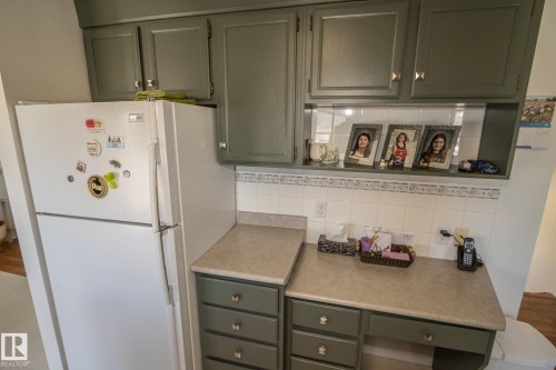 Kitchen area featuring sage green cabinetry, a built-in display shelf, and white tile backsplash - 4417 46A St, St. Paul Town, AB - Indoor Photo Showing Kitchen