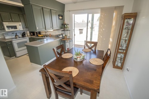 Kitchen and dining area featuring sage green cabinetry, white appliances, a light-colored countertop, and a tile backsplash - 4417 46A St, St. Paul Town, AB - Indoor Photo Showing Other Room