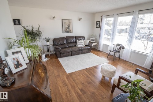 Living area featuring wood-finish flooring, white walls, and a large window bank with white trim - 4417 46A St, St. Paul Town, AB - Indoor Photo Showing Living Room