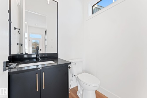 Well-appointed bathroom featuring a dark vanity with gold hardware, a black countertop, and a contemporary black faucet - 11019 132 St, Edmonton, AB - Indoor Photo Showing Bathroom