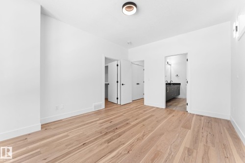 This room features light hardwood flooring, white walls, and a modern ceiling light fixture - 11019 132 St, Edmonton, AB - Indoor Photo Showing Other Room