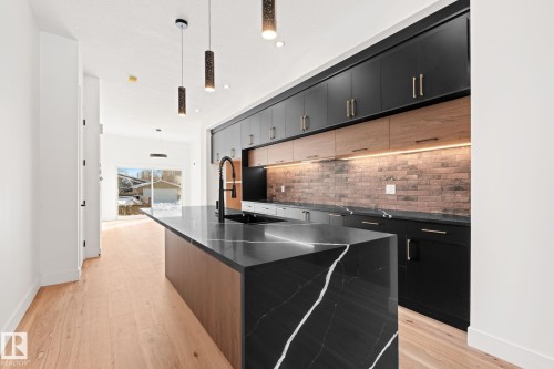 The kitchen features a striking black island with white veining, complemented by black cabinetry and wood-toned elements - 11019 132 St, Edmonton, AB - Indoor Photo Showing Kitchen With Upgraded Kitchen