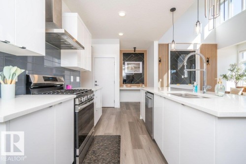 Contemporary kitchen featuring white flat-panel cabinetry, a stainless steel gas range with coordinating hood, and a gray tile backsplash - 5627 Kootook Place, Edmonton, AB - Indoor Photo Showing Kitchen With Upgraded Kitchen
