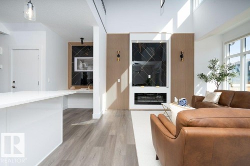 Open-concept living space featuring wood-finish flooring and a white kitchen island with an extended counter - 5627 Kootook Place, Edmonton, AB - Indoor Photo Showing Living Room With Fireplace