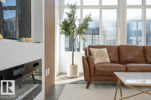 Living area featuring an electric fireplace with a glass front, a wood-finish slatted accent wall, and expansive multi-pane windows - 5627 Kootook Place, Edmonton, AB - Indoor Photo Showing Living Room