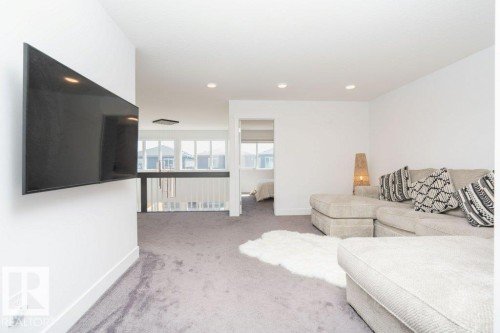 Carpeted loft area featuring a mounted television, recessed lighting, and a white railing overlooking the floor below - 5627 Kootook Place, Edmonton, AB - Indoor