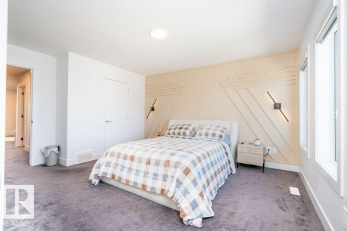 Carpeted room featuring a decorative accent wall with geometric wood paneling, two vertical wall sconces, recessed ceiling lighting, and multiple windows with white trim - 5627 Kootook Place, Edmonton, AB - Indoor Photo Showing Bedroom