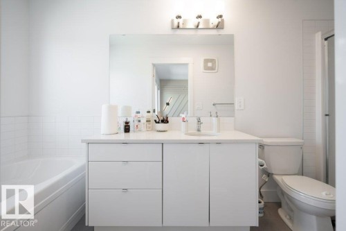 Bathroom featuring a white vanity with integrated sink, a rectangular wall-mounted mirror, and a three-light fixture - 5627 Kootook Place, Edmonton, AB - Indoor Photo Showing Bathroom