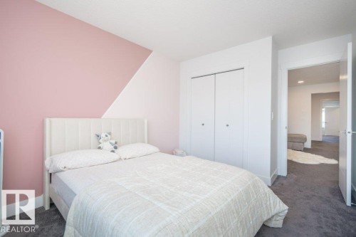 Bedroom featuring a white upholstered headboard, two-tone painted walls with a geometric design, grey carpet flooring, and a double-door closet with spherical hardware - 5627 Kootook Place, Edmonton, AB - Indoor Photo Showing Bedroom