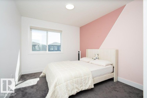 Bedroom with dark grey carpeting, a large window, white trim, and a feature wall with a two-tone geometric paint design - 5627 Kootook Place, Edmonton, AB - Indoor Photo Showing Bedroom