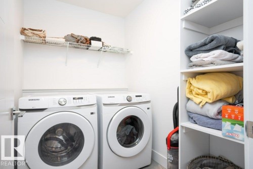 Dedicated laundry space featuring a side-by-side washer and dryer set, white wire shelving, and built-in white cabinetry with additional shelving - 5627 Kootook Place, Edmonton, AB - Indoor Photo Showing Laundry Room