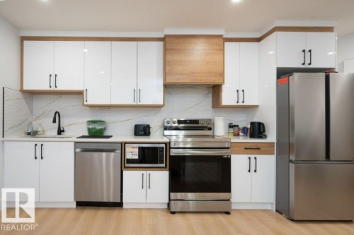 Contemporary kitchen featuring white cabinetry with wood-finish accents and matte black hardware - 5627 Kootook Place, Edmonton, AB - Indoor Photo Showing Kitchen With Upgraded Kitchen