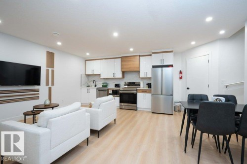 Open-concept living space featuring wood-finish flooring, recessed lighting, and a contemporary kitchen with stainless steel appliances - 5627 Kootook Place, Edmonton, AB - Indoor