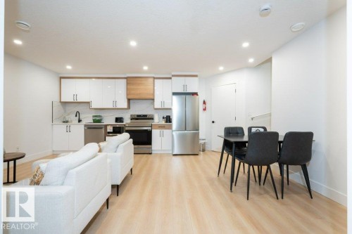 Open-concept living space featuring wood-finish flooring, recessed lighting, a kitchen with white cabinetry, stainless steel appliances, and a dining area - 5627 Kootook Place, Edmonton, AB - Indoor Photo Showing Kitchen