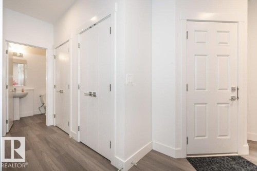 Entryway featuring a paneled door with brushed nickel hardware, wood-finish flooring, and white baseboards - 5627 Kootook Place, Edmonton, AB - Indoor Photo Showing Other Room