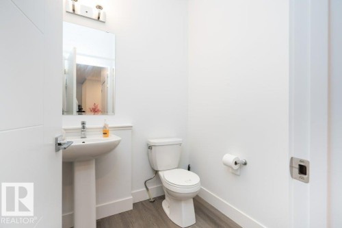 Pedestal sink with chrome hardware and a rectangular mirror, complemented by a contemporary light fixture - 5627 Kootook Place, Edmonton, AB - Indoor Photo Showing Bathroom