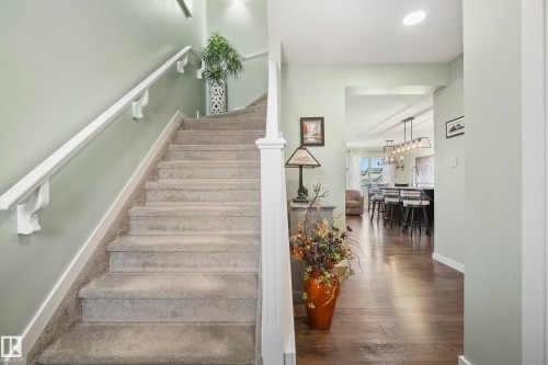 Carpeted staircase with white handrails, complemented by wood-finish flooring and a recessed lighting fixture - 6504 59 Avenue, Beaumont, AB - Indoor Photo Showing Other Room