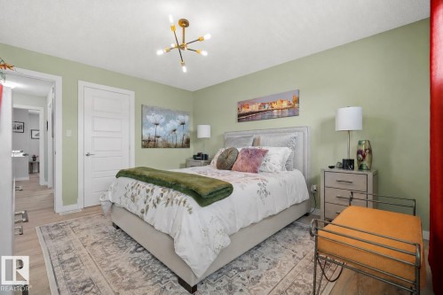 Wood-finish flooring throughout, complemented by a contemporary light fixture - 6504 59 Avenue, Beaumont, AB - Indoor Photo Showing Bedroom