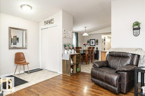 Spacious interior featuring wood-finish flooring, light-toned walls, and a convenient entry area with tile flooring and a built-in closet - 1637 68 Avenue, Edmonton, AB - Indoor Photo Showing Living Room