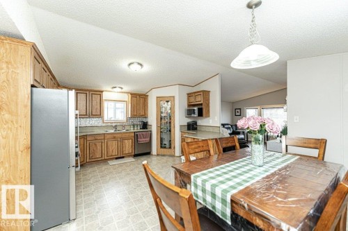 Spacious kitchen and dining area featuring wood-finish cabinetry, stainless steel appliances, a tiled backsplash, and a pantry with a glass-paneled door - 1637 68 Avenue, Edmonton, AB - Indoor Photo Showing Dining Room