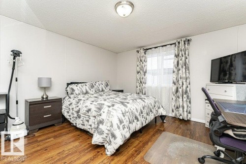 Spacious room featuring wood-finish flooring, white paneled walls, and a window with blinds - 1637 68 Avenue, Edmonton, AB - Indoor Photo Showing Bedroom
