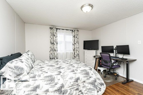 Bedroom featuring white panel walls, wood-finish flooring, and a window with blinds - 1637 68 Avenue, Edmonton, AB - Indoor Photo Showing Bedroom