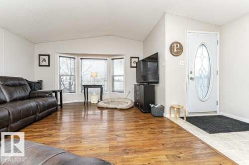 Living area featuring wood-finish flooring, a bay window with blinds, and a vaulted ceiling - 1637 68 Avenue, Edmonton, AB - Indoor Photo Showing Living Room