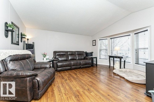 Spacious living area featuring wood-finish flooring, a vaulted ceiling, and ample natural light from a bay window - 1637 68 Avenue, Edmonton, AB - Indoor Photo Showing Living Room