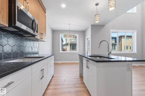 Modern kitchen featuring a sleek island with an undermount sink and gooseneck faucet - 3714 40 Avenue, Beaumont, AB - Indoor Photo Showing Kitchen With Upgraded Kitchen