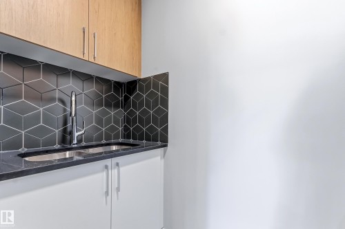 Modern utility sink with a chrome faucet, set against a black geometric tile backsplash - 3714 40 Avenue, Beaumont, AB - Indoor Photo Showing Kitchen