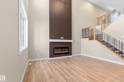 Soaring vaulted ceilings define this inviting living space, featuring a floor-to-ceiling accent wall with a built-in electric fireplace - 3714 40 Avenue, Beaumont, AB - Indoor With Fireplace