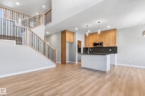 Open-concept living space featuring wood-finish flooring, a contemporary staircase with black metal balusters, and recessed lighting - 3714 40 Avenue, Beaumont, AB - Indoor Photo Showing Kitchen