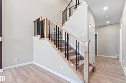Expansive staircase featuring light wood-finish railings with black iron balusters and carpeted treads - 3714 40 Avenue, Beaumont, AB - Indoor Photo Showing Other Room