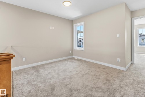 Carpeted interior space with neutral wall tones and white baseboards - 3714 40 Avenue, Beaumont, AB - Indoor Photo Showing Other Room