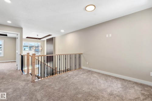 Carpeted landing area featuring a light wood and black iron baluster railing, recessed lighting, and a flush-mount ceiling fixture - 3714 40 Avenue, Beaumont, AB - Indoor Photo Showing Other Room