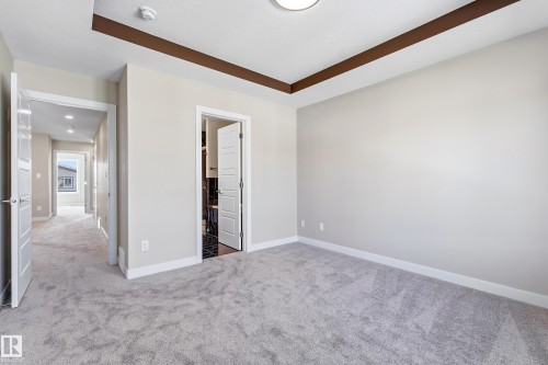 Spacious room featuring light gray carpeting, a tray ceiling with dark wood-finish trim, and recessed lighting - 3714 40 Avenue, Beaumont, AB - Indoor Photo Showing Other Room