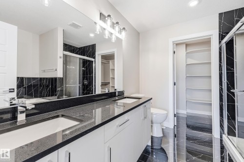 Dual vanity with integrated sinks, dark stone countertops, and modern chrome fixtures - 3714 40 Avenue, Beaumont, AB - Indoor Photo Showing Bathroom