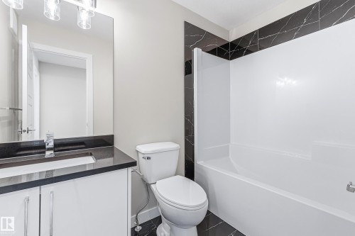 Bathroom featuring a white vanity with dark countertop, undermount sink, and chrome faucet - 3714 40 Avenue, Beaumont, AB - Indoor Photo Showing Bathroom