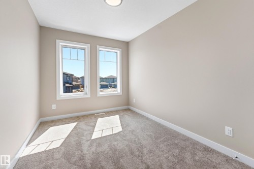 Room featuring two large windows, neutral wall paint, white trim, gray carpeting, and a flush-mount ceiling light fixture - 3714 40 Avenue, Beaumont, AB - Indoor Photo Showing Other Room