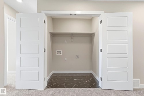 Utility closet featuring bi-fold panel doors, a built-in shelf, and dark-toned tiled flooring with light veining - 3714 40 Avenue, Beaumont, AB - Indoor Photo Showing Other Room