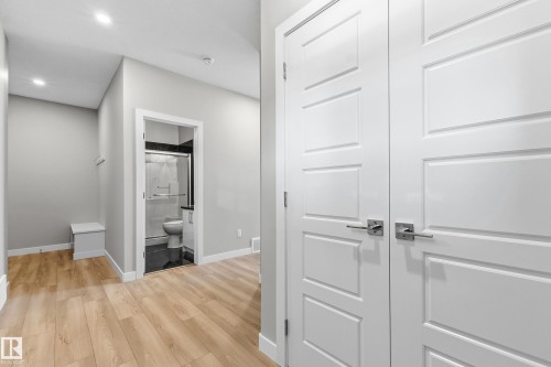 Contemporary interior hallway featuring wood-finish flooring, white paneled doors with brushed nickel hardware, light gray wall paint, and recessed ceiling lighting - 3714 40 Avenue, Beaumont, AB - Indoor Photo Showing Other Room