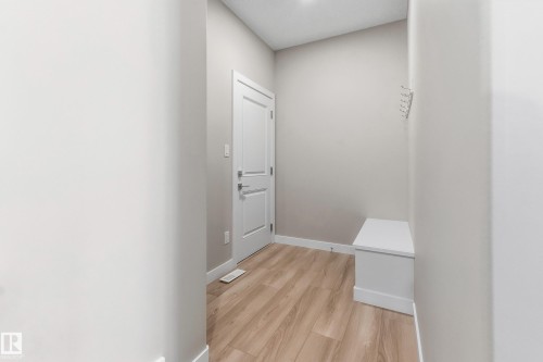 Entryway featuring wood-finish flooring, light-toned walls, white trim, and a built-in storage bench - 3714 40 Avenue, Beaumont, AB - Indoor Photo Showing Other Room
