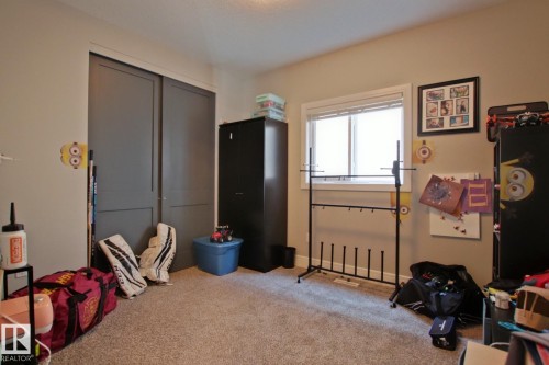 Carpeted room featuring a double-pane window, flush-mount lighting, and bi-fold closet doors - 9711 223 Street, Edmonton, AB 
