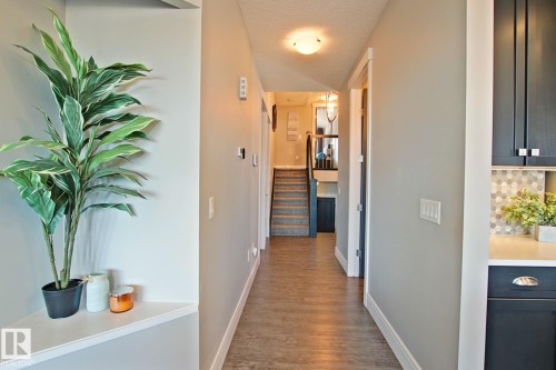 Hallway with wood-finish flooring, light neutral wall paint, and white trim - 9711 223 Street, Edmonton, AB 