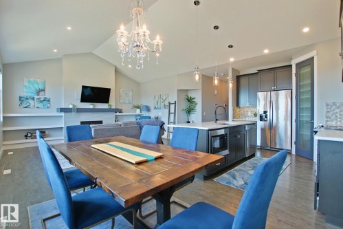 Open-concept living space featuring a vaulted ceiling with a chandelier, a contemporary fireplace, and built-in shelving - 9711 223 Street, Edmonton, AB 
