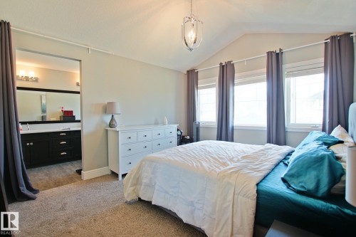 Carpeted room featuring a vaulted ceiling and a polished chrome pendant light fixture - 9711 223 Street, Edmonton, AB 