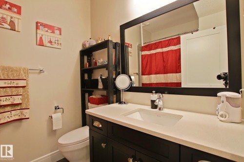 Bathroom vanity with a rectangular undermount sink, light-toned countertop, and dark wood-finish cabinetry - 9711 223 Street, Edmonton, AB 