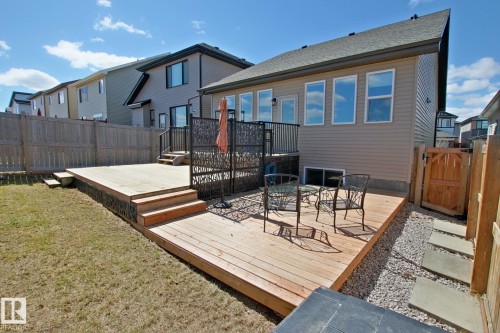 Expansive multi-level wood-finish deck with integrated steps, surrounded by a manicured lawn and a privacy fence - 9711 223 Street, Edmonton, AB 