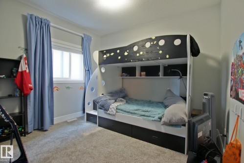 Bedroom featuring wall-to-wall carpeting, a double window with blinds and curtain rods, and a multi-level bunk bed with integrated shelving and drawer storage - 9711 223 Street, Edmonton, AB 