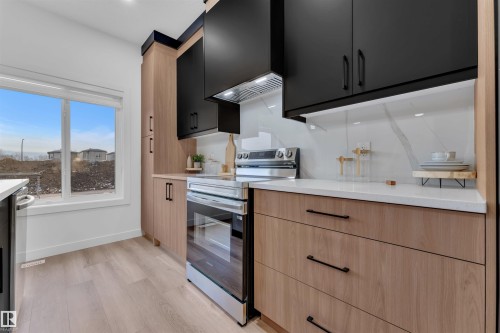Modern kitchen featuring black upper cabinetry, wood-finish lower cabinetry, and quartz countertops - 269 Falcon Crescent, Leduc, AB - Indoor Photo Showing Kitchen